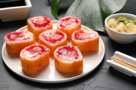 Foto de Deliciosos rollos de sushi con salmón y tobiko sobre mesa texturizada gris, primer plano - Imagen libre de derechos