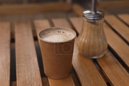 Photo for Takeaway paper cup with coffee near brown sugar on wooden table, closeup - Royalty Free Image