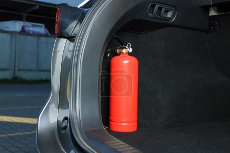Red fire extinguisher in trunk, space for text. Car safety equipment