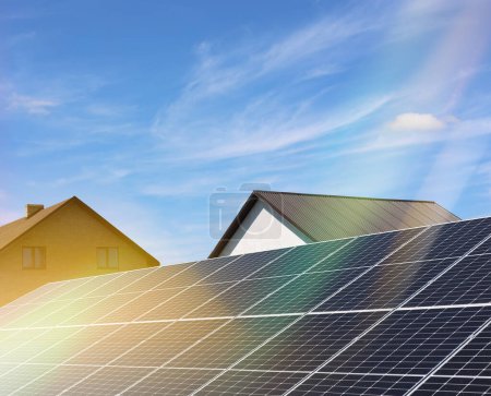 Foto de Paneles solares cerca de casas bajo el cielo azul en un día soleado. Fuente de energía alternativa - Imagen libre de derechos