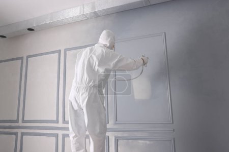 Dekorateur färbt Wand in grauer Farbe mit Sprühfarbe