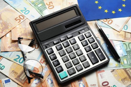 Calculator, glasses and pen on banknotes, closeup. Eurobonds concept