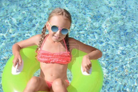 Photo for Cute little girl with sunglasses and inflatable ring in pool on sunny day - Royalty Free Image