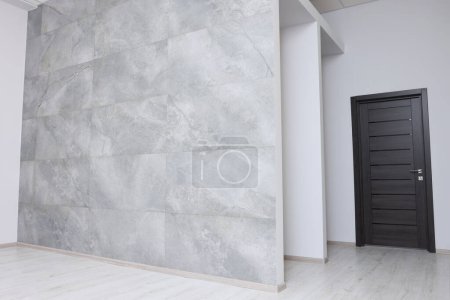 Foto de Habitación vacía con pared de azulejos y puerta de madera durante la reparación - Imagen libre de derechos