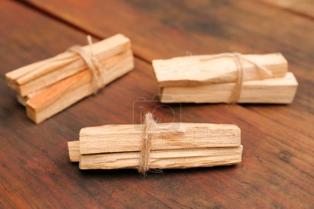 Photo for Bunches of tied Palo Santo sticks on wooden table, closeup - Royalty Free Image
