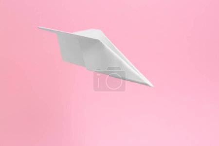 Foto de Plano de papel blanco volando sobre fondo rosa, espacio para texto - Imagen libre de derechos