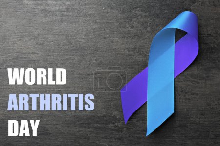 Día Mundial de la Artritis. Cinta de conciencia azul y púrpura sobre fondo gris oscuro, vista superior