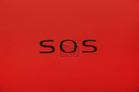 Foto de Abreviatura SOS (Save Our Souls) escrito sobre fondo rojo, vista superior - Imagen libre de derechos