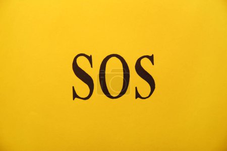 Foto de Abreviatura SOS (Save Our Souls) escrito sobre fondo amarillo, vista superior - Imagen libre de derechos