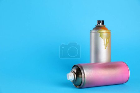 Photo for Used cans of spray paints on light blue background. Space for text - Royalty Free Image