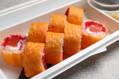 Foto de Deliciosos rollos de sushi mamenori en recipiente de plástico en la mesa, primer plano. Entrega de alimentos - Imagen libre de derechos