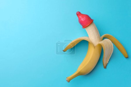 Téléchargez les photos : Banane avec préservatif sur fond bleu clair, vue de dessus et espace pour le texte. Concept de sexe sûr - en image libre de droit