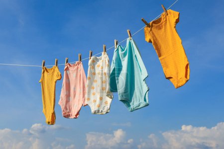 Limpiar los bebés que cuelgan de la línea de lavado contra el cielo. Ropa de secado