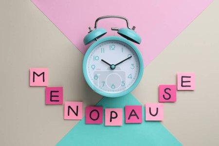 Photo for Pink paper notes with word Menopause and alarm clock on color background, flat lay - Royalty Free Image