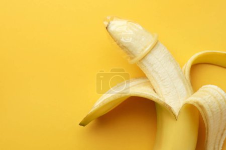 Téléchargez les photos : Banane avec préservatif sur fond orange, vue du dessus et espace pour le texte. Concept de sexe sûr - en image libre de droit