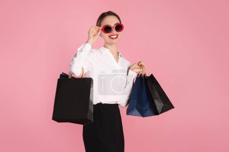 Téléchargez les photos : Joyeux jeune femme avec des sacs à provisions sur fond rose clair. Grande vente - en image libre de droit