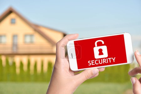 System der inneren Sicherheit. Frau mit Smartphone in der Nähe ihres Hauses im Freien, Nahaufnahme