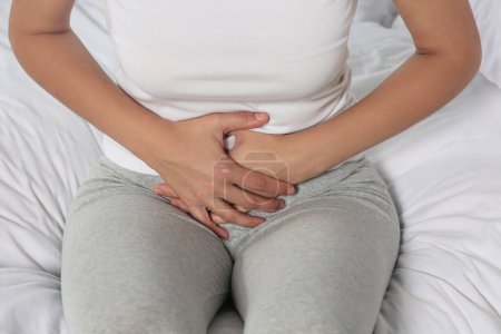 Young woman suffering from cystitis on bed, closeup