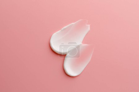 Sample facial cream on pink background, top view