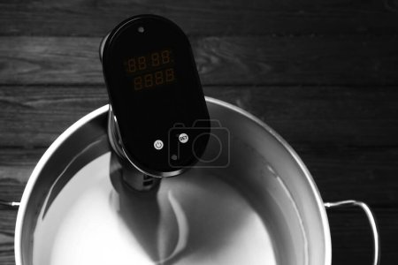 Téléchargez les photos : Cirateur d'immersion thermique en pot sur table en bois noir, vue de dessus. Cuisinière Sous vide - en image libre de droit