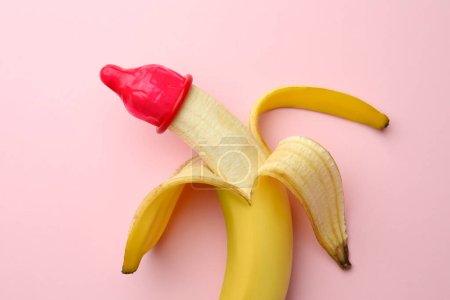 Foto de Plátano con condón sobre fondo rosa, vista superior. Concepto de sexo seguro - Imagen libre de derechos
