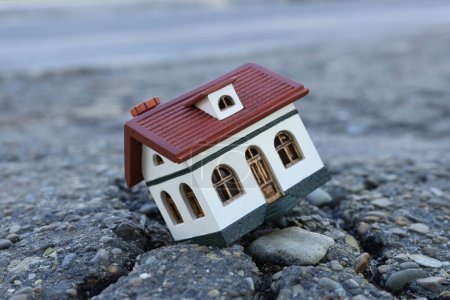 Téléchargez les photos : Modèle de maison en asphalte fissuré. Catastrophe sismique - en image libre de droit