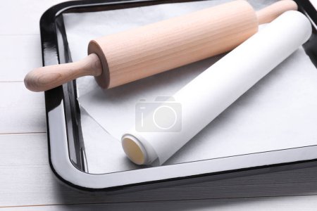 Téléchargez les photos : Plat à pâtisserie avec papier parchemin et rouleau à pâtisserie sur table en bois blanc, gros plan - en image libre de droit