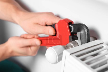 fontanero profesional que utiliza la llave ajustable para instalar el nuevo radiador de calefacción, primer plano