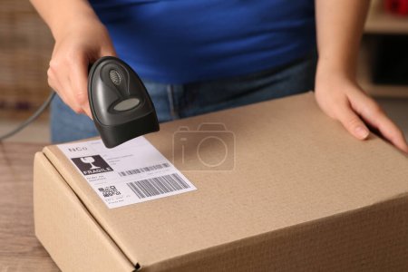 Postangestellte mit Scanner liest Paketbarcode am Schalter, Nahaufnahme