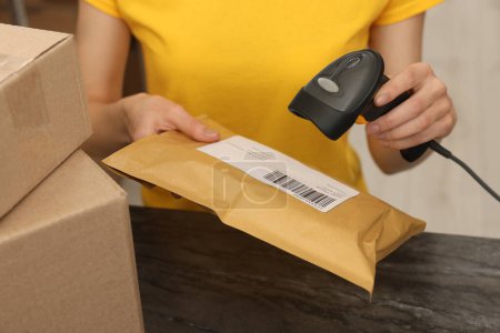 Postangestellte mit Scanner liest Paketbarcode am Schalter drinnen, Nahaufnahme