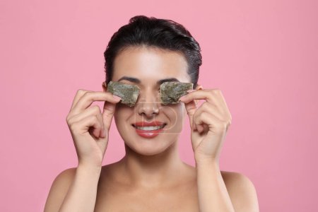 Photo for Woman covering eyes with tea bags on pink background. Skin care - Royalty Free Image