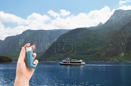 Photo for Woman with asthma inhaler near lake, closeup. Emergency first aid during outdoor recreation - Royalty Free Image