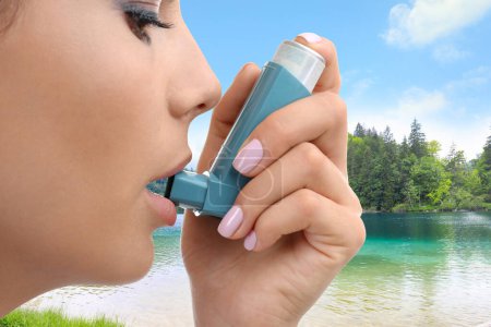 Photo for Woman using asthma inhaler near lake, closeup. Emergency first aid during outdoor recreation - Royalty Free Image