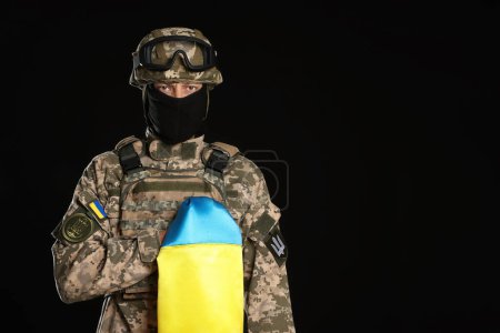 Photo for Soldier in military uniform with Ukrainian flag on black background. Space for text - Royalty Free Image