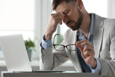 Téléchargez les photos : Homme souffrant de fatigue oculaire au bureau, se concentrer sur la main avec des lunettes - en image libre de droit