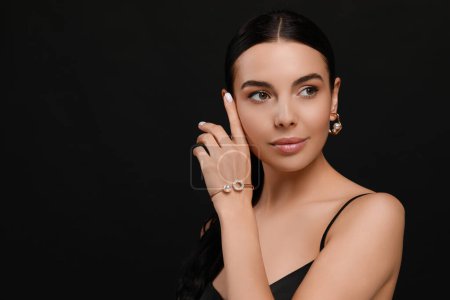 Foto de Mujer joven con elegantes joyas de perlas sobre fondo negro, espacio para el texto - Imagen libre de derechos