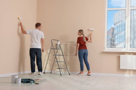 Téléchargez les photos : Couple mur de peinture dans l'appartement pendant la réparation - en image libre de droit
