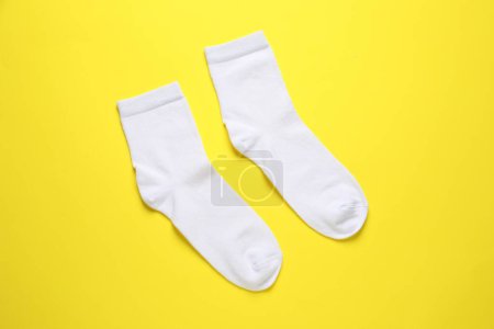 Pair of white socks on yellow background, flat lay