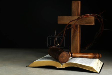 Juez martillo, biblia, cruz de madera y corona de espinas sobre mesa gris. Espacio para texto