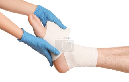 Téléchargez les photos : Médecin appliquant un bandage médical sur le pied du patient sur fond blanc, gros plan - en image libre de droit