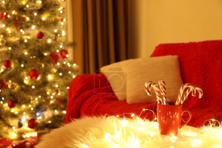 Photo for Red cup with candy canes on faux fur in room decorated for Christmas. Interior design - Royalty Free Image