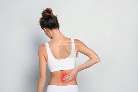 Foto de Mujer que sufre de dolor de espalda sobre fondo gris claro - Imagen libre de derechos
