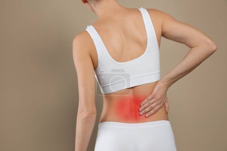 Foto de Mujer que sufre de dolor en la espalda sobre fondo beige, primer plano - Imagen libre de derechos