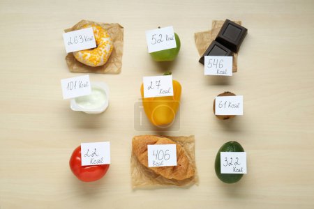 Photo for Food products with calorific value tags on wooden table, flat lay. Weight loss concept - Royalty Free Image