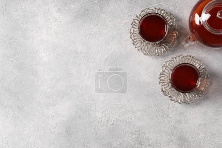 Téléchargez les photos : Verres de thé traditionnel turc en porte-cru et casserole sur table gris clair, pose plate. Espace pour le texte - en image libre de droit