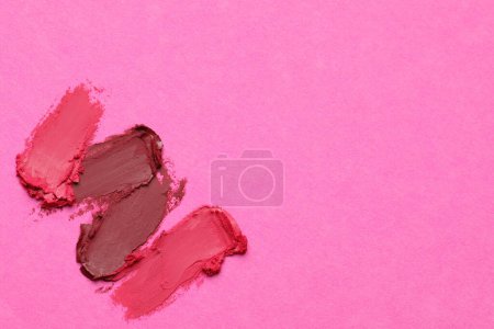 Smears of bright lipsticks on pink background, top view. Space for text
