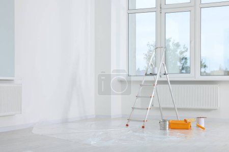 Téléchargez les photos : Escalier et outils de peinture près de la fenêtre dans une pièce vide, espace pour le texte - en image libre de droit