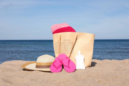 Photo for Summer bag with beach accessories on sand near sea - Royalty Free Image