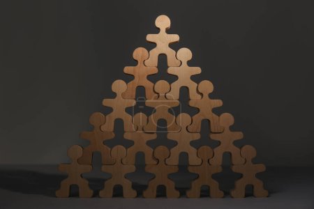 Foto de Proceso de contratación, concepto de competencia laboral. Pirámide de figuras humanas de madera con una notable en la parte superior como primer solicitante en la mesa gris - Imagen libre de derechos