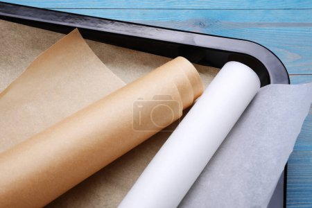 Téléchargez les photos : Rouleaux de papier parchemin dans une plaque à pâtisserie sur une table en bois bleu clair, gros plan - en image libre de droit